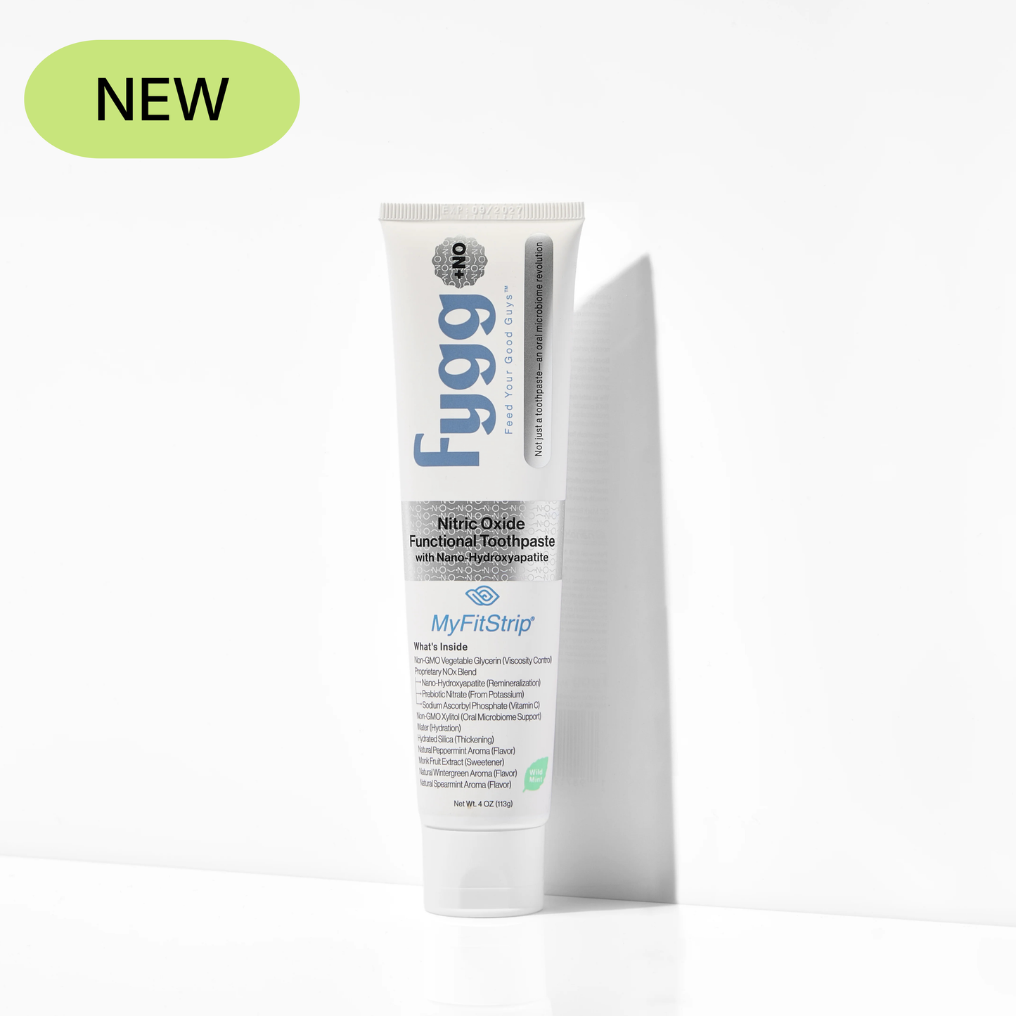 A tube of Fygg MyFitStrip functional toothpaste stands upright against a white wall, casting a soft shadow. A light green oval badge in the top-left corner reads 'NEW'.
